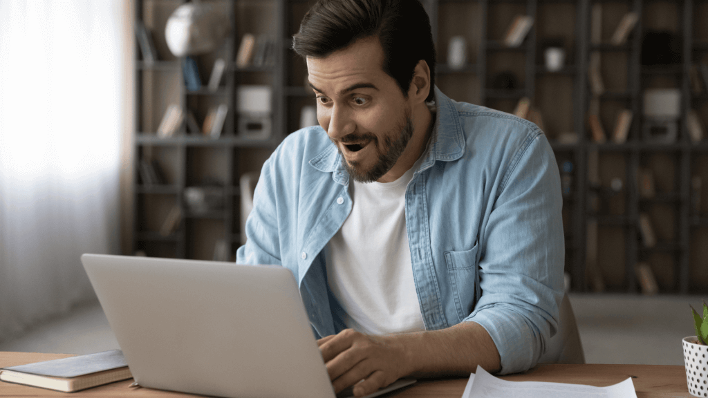 Homme qui regarde son ordinateur avec un air surpris en découvrant les bénéfices du bilan de compétences