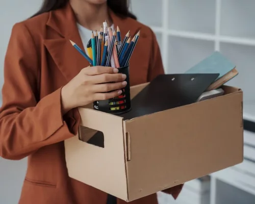 Femme qui tient un carton avec ses affaires et qui quitte son travail