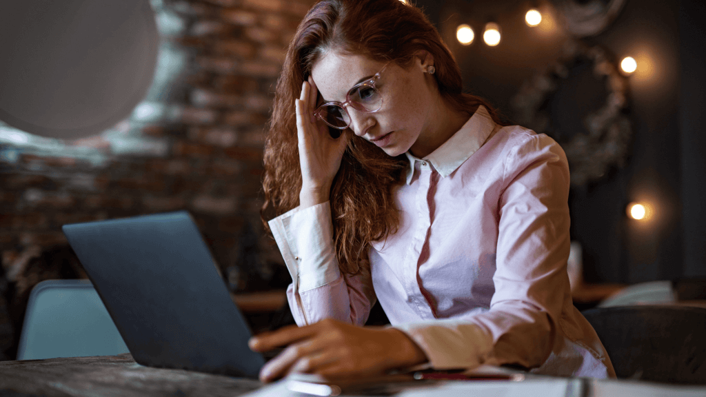 Femme rousse qui recherche sur son ordinateur pour comprendre le fonctionnement de l'outplacement.